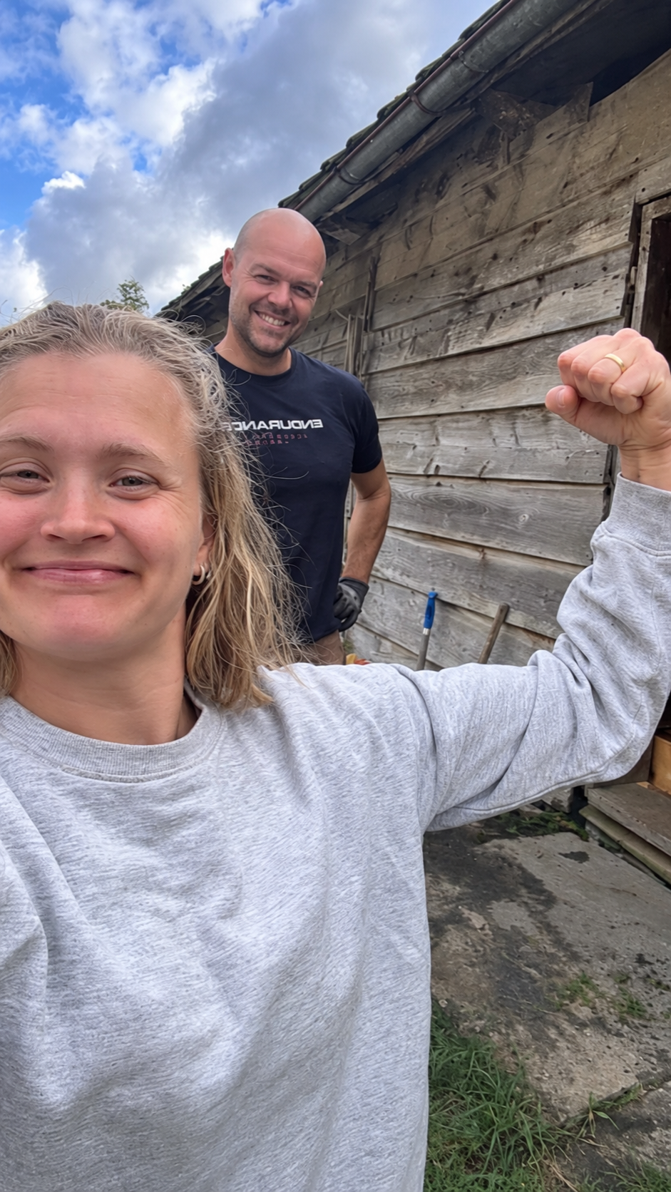 Jarle og Elin Mari ved tømmerveggen på garden